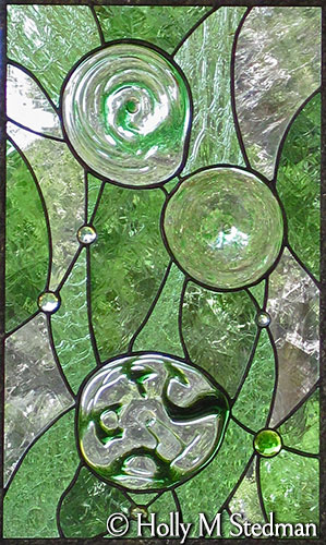 Green stained glass panel with flowing, geometric design