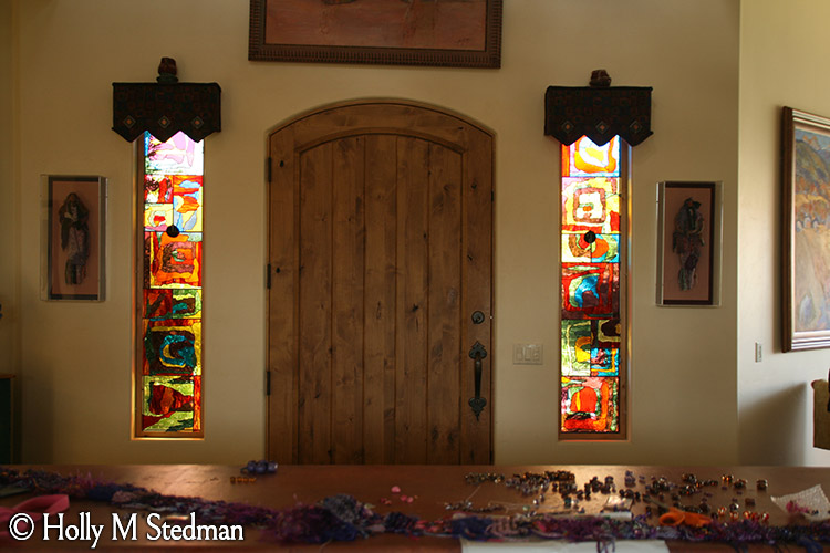 Two colorful stained glass windows on either side of a door