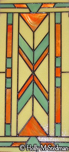 Three-piece stained glass window with white, orange and turquoise geometric design, panel 2
