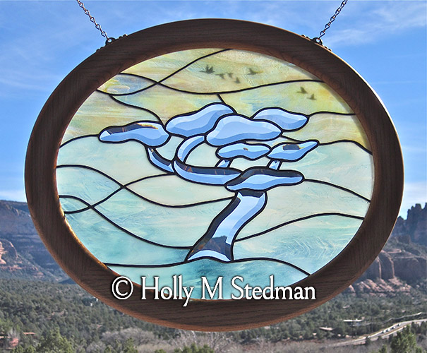 Circular stained glass panel of a bevelled tree