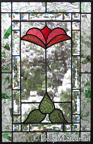 Geometric stained glass panel of red flower and bevels