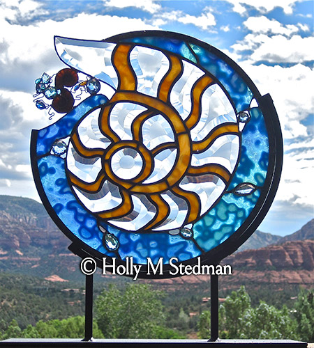 Stained glass sculpture of nautilus shell with blue background
